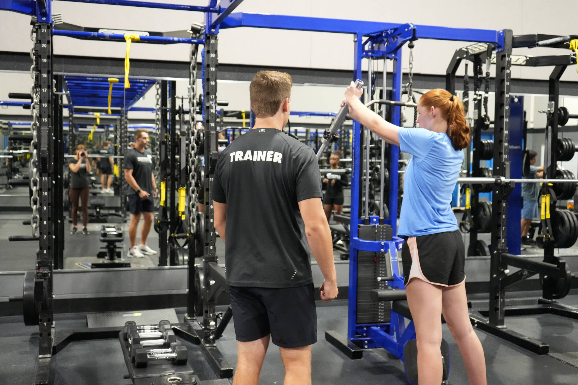 personal trainer coaching a client in weight room